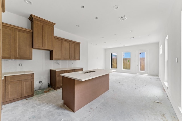 6705 Del Rio St, Houston, TX 77021 - kitchen with brown cabinetry, a kitchen island with sink, open floor plan, and light countertops
