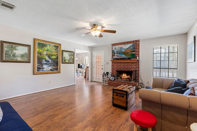 9219 Sendera Dr, Magnolia, TX 77354 - living area featuring wood finished floors, a ceiling fan, a fireplace, a textured ceiling, and baseboards