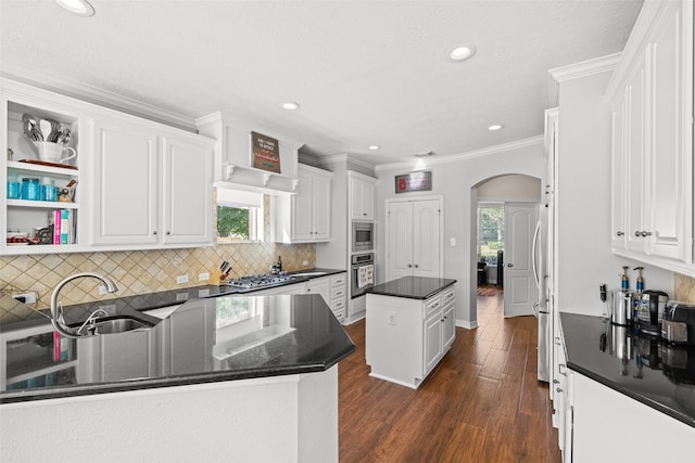 15106 Aragon Green Dr, Cypress, TX 77433 - kitchen featuring stainless steel appliances, arched walkways, a kitchen island, a sink, and white cabinetry