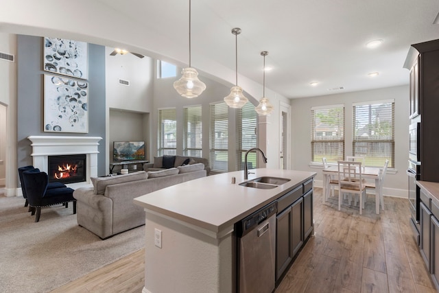 17505 Spice Merlot Ln, Conroe, TX 77302 - kitchen featuring a sink, stainless steel appliances, a glass covered fireplace, light wood-type flooring, and light countertops