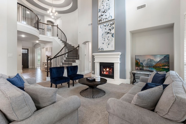 17505 Spice Merlot Ln, Conroe, TX 77302 - living room featuring arched walkways, a towering ceiling, a glass covered fireplace, stairway, and a chandelier