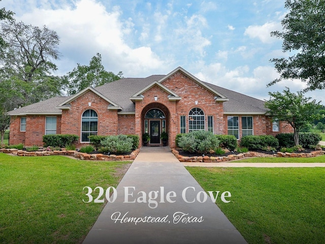320 Eagle Cv, Hempstead, TX 77445 - view of front of home with brick siding, a front yard, and a shingled roof