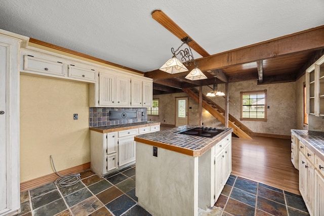 13415 Bayonne Cir, Tomball, TX 77377 - kitchen with black electric stovetop, baseboards, beamed ceiling, stone tile flooring, and pendant lighting