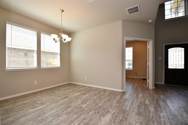 entryway featuring a chandelier, light wood finished floors, and baseboards