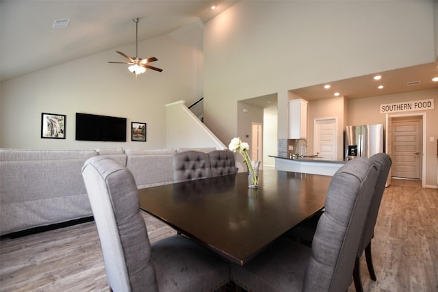 dining area featuring high vaulted ceiling, light wood-type flooring, stairs, a ceiling fan, and recessed lighting