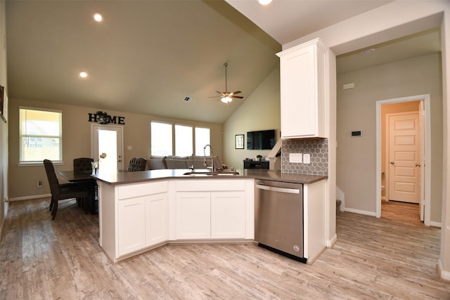 kitchen with stainless steel dishwasher, a sink, a peninsula, open floor plan, and white cabinetry