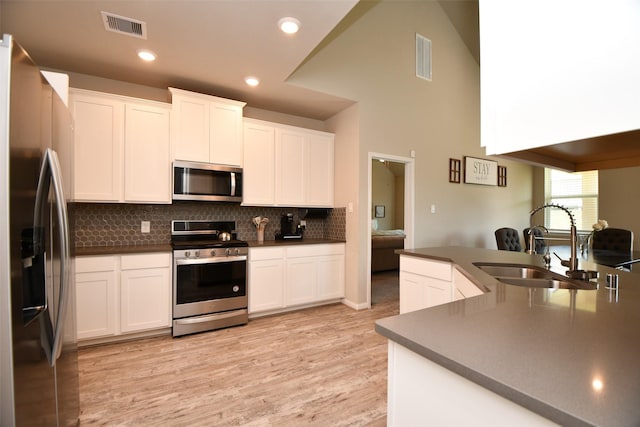 kitchen featuring stainless steel appliances, a sink, dark countertops, light wood finished floors, and recessed lighting