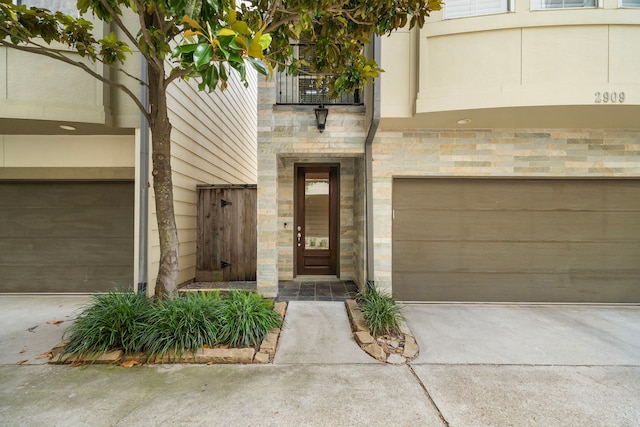 2909 Pease St, Houston, TX 77003 - doorway to property featuring a garage, driveway, and stone siding