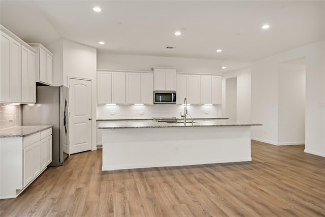 177 Jim Hall Ln, New Waverly, TX 77358 - kitchen featuring appliances with stainless steel finishes, decorative backsplash, an island with sink, recessed lighting, and white cabinets