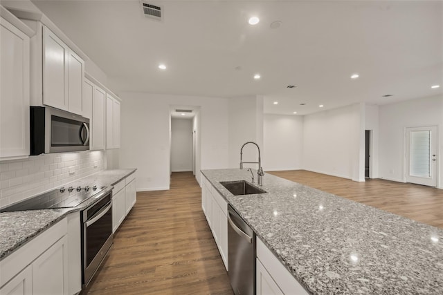 177 Jim Hall Ln, New Waverly, TX 77358 - kitchen with stainless steel appliances, backsplash, white cabinetry, light stone counters, and light wood-style floors