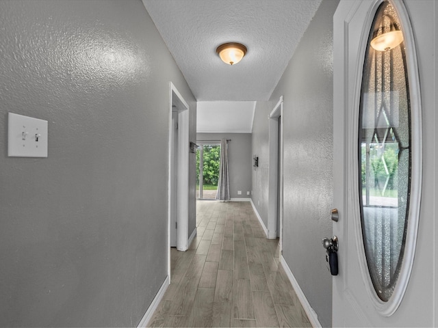 11731 Flushing Meadows Dr, Houston, TX 77089 - hall with baseboards, a textured wall, light wood-style flooring, and a textured ceiling