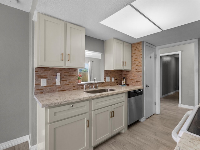 11731 Flushing Meadows Dr, Houston, TX 77089 - kitchen with stainless steel dishwasher, a sink, backsplash, light wood finished floors, and baseboards