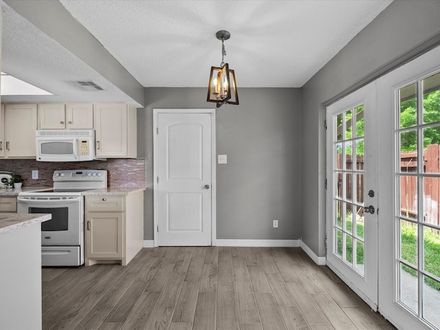 11731 Flushing Meadows Dr, Houston, TX 77089 - kitchen with white appliances, light wood-style flooring, baseboards, tasteful backsplash, and a chandelier