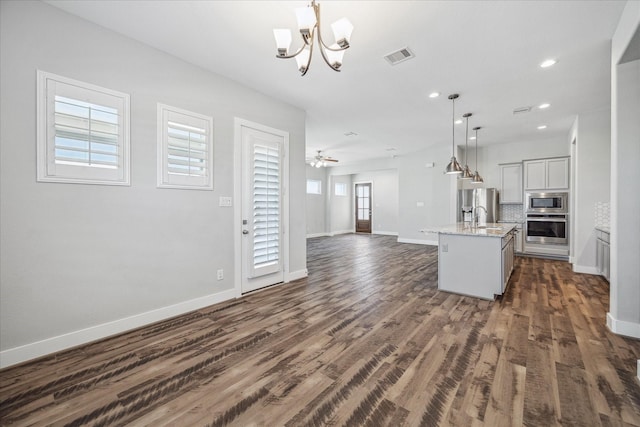 10022 Waving Grain Ln, Houston, TX 77080 - kitchen with stainless steel appliances, open floor plan, a chandelier, baseboards, and dark wood-type flooring
