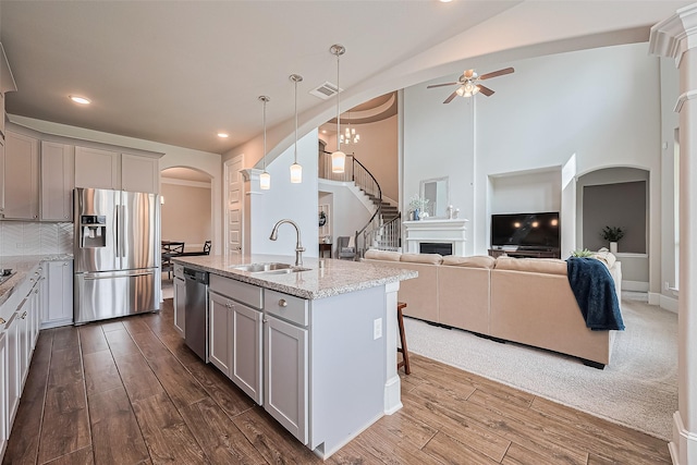 16826 Ellicott Rock Dr, Humble, TX 77346 - kitchen featuring appliances with stainless steel finishes, a sink, arched walkways, ceiling fan, and dark wood-style flooring