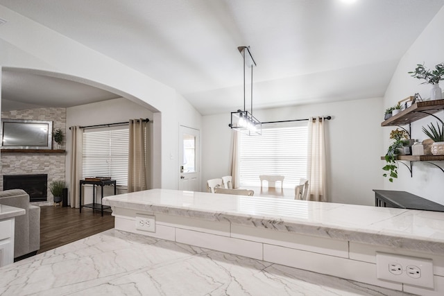 4108 S Meridian Greens Dr, Dickinson, TX 77539 - kitchen featuring open shelves, a fireplace, arched walkways, lofted ceiling, and light stone countertops
