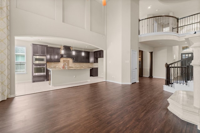 27303 Balson Forest Ln, Spring, TX 77386 - unfurnished living room with dark wood finished floors, a high ceiling, baseboards, stairs, and ornate columns