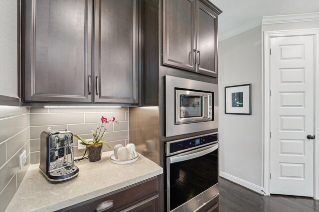 13710 Nubenbrook Lake Dr, Houston, TX 77044 - kitchen with stainless steel appliances, dark brown cabinets, crown molding, decorative backsplash, and baseboards