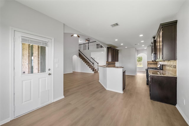 11915 Eagle Ridge Dr, Mont Belvieu, TX 77535 - kitchen with arched walkways, dark brown cabinetry, light wood-style flooring, and recessed lighting