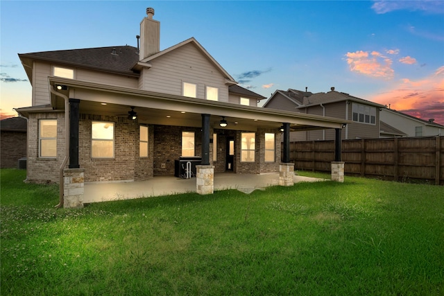 11915 Eagle Ridge Dr, Mont Belvieu, TX 77535 - back of house at dusk featuring a ceiling fan, a patio area, a chimney, and brick siding