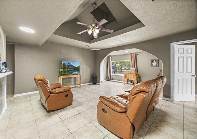 12910 Green River Dr, Houston, TX 77044 - living room featuring arched walkways, a textured ceiling, a tray ceiling, a ceiling fan, and light tile patterned floors