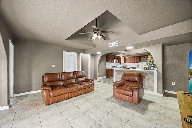 12910 Green River Dr, Houston, TX 77044 - living room featuring arched walkways, a textured wall, a textured ceiling, a ceiling fan, and light tile patterned floors