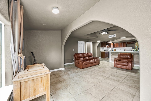 12910 Green River Dr, Houston, TX 77044 - living area featuring arched walkways, a textured wall, ceiling fan, a textured ceiling, and light tile patterned floors