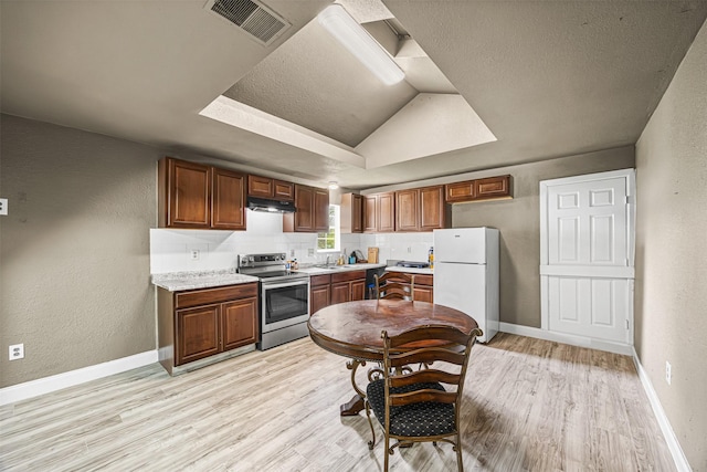12910 Green River Dr, Houston, TX 77044 - kitchen with electric range, freestanding refrigerator, under cabinet range hood, light wood finished floors, and a textured wall