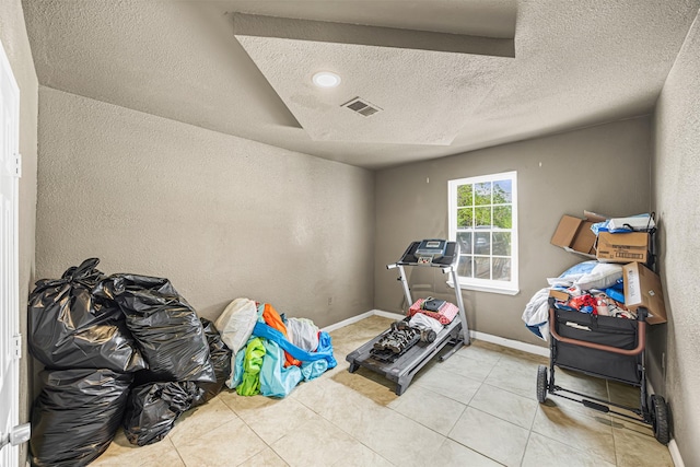 12910 Green River Dr, Houston, TX 77044 - exercise room with a textured ceiling, light tile patterned flooring, a textured wall, and baseboards