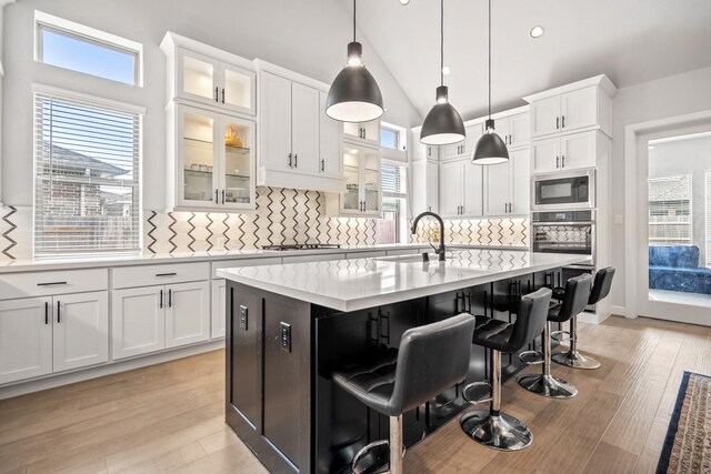 24515 Green Buffalograss Trl, Katy, TX 77493 - kitchen with stainless steel oven, a sink, light countertops, a breakfast bar area, and decorative backsplash