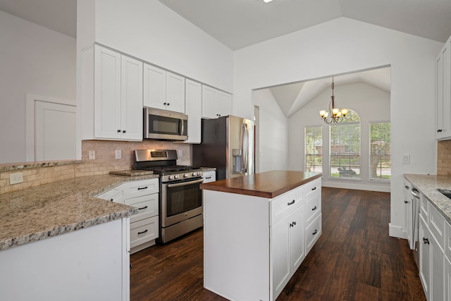 20711 Medallion Pointe Dr, Katy, TX 77450 - kitchen featuring appliances with stainless steel finishes, lofted ceiling, dark wood-style flooring, white cabinetry, and dark stone counters