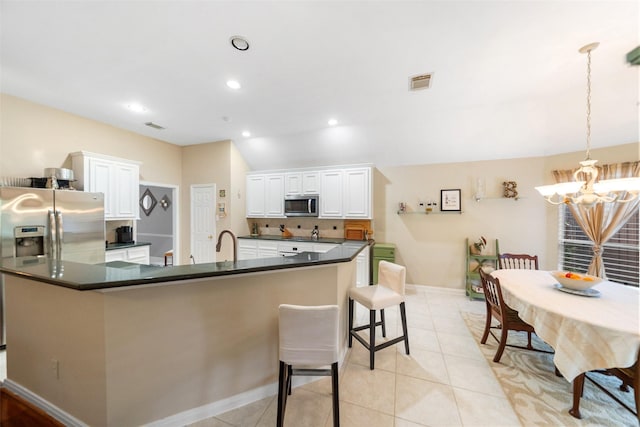 7410 Fall Creek Bnd, Humble, TX 77396 - kitchen with stainless steel appliances, a chandelier, dark countertops, white cabinets, and baseboards