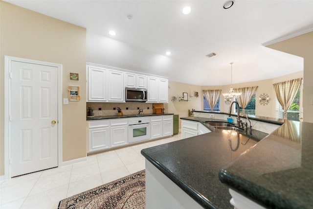 7410 Fall Creek Bnd, Humble, TX 77396 - kitchen featuring stainless steel microwave, white oven, a sink, a chandelier, and tasteful backsplash
