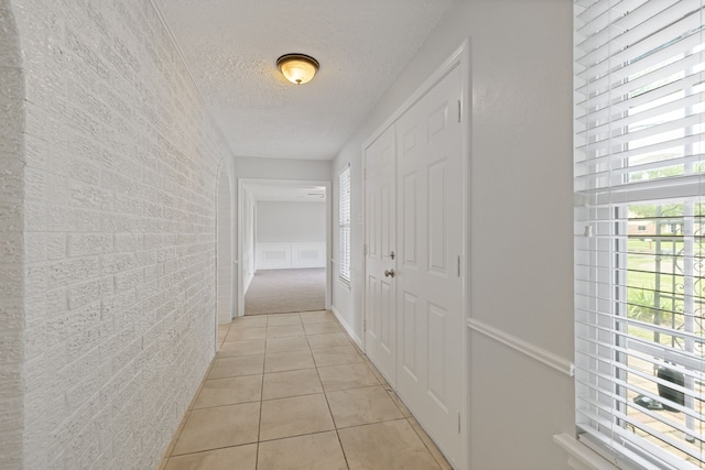 6003 Green Falls Dr, Houston, TX 77088 - hallway featuring a textured ceiling, light tile patterned floors, and brick wall
