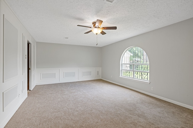 6003 Green Falls Dr, Houston, TX 77088 - empty room with a ceiling fan, carpet floors, a textured ceiling, a decorative wall, and wainscoting