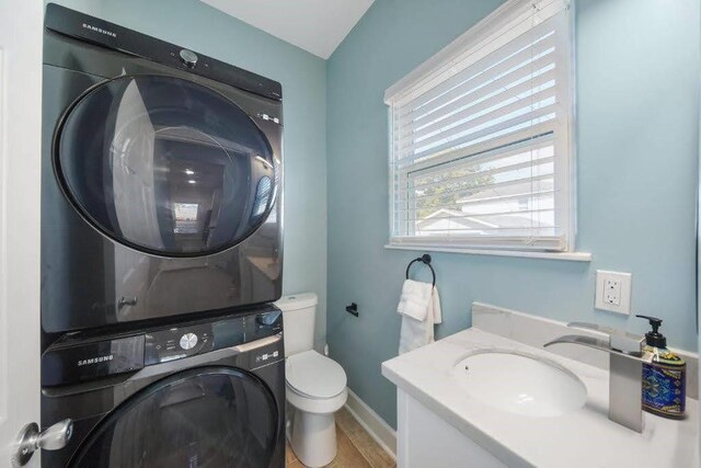 4702 Avenue N 1/2 Avenue, Galveston, TX 77551 - half bath featuring stacked washing machine and dryer, baseboards, toilet, vanity, and wood finished floors
