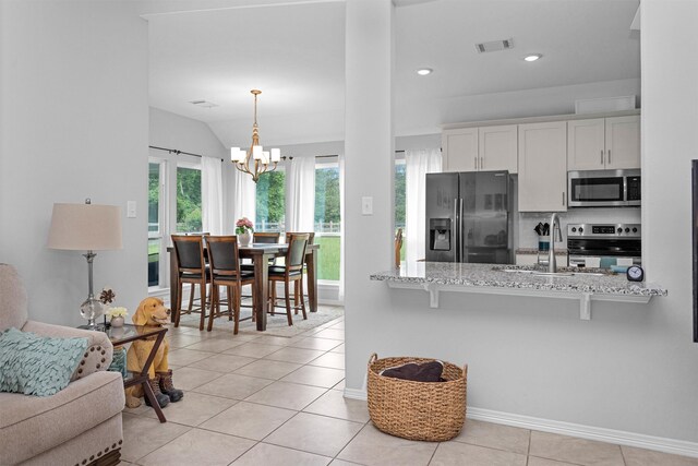12 Oakland Ct, Huntsville, TX 77340 - kitchen with appliances with stainless steel finishes, light stone countertops, a chandelier, a breakfast bar, and white cabinetry