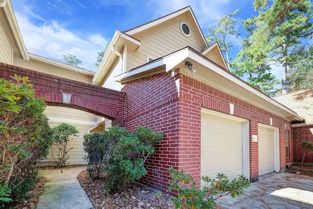 43 S Avonlea Cir, The Woodlands, TX 77382 - view of side of home featuring brick siding, a garage, and driveway
