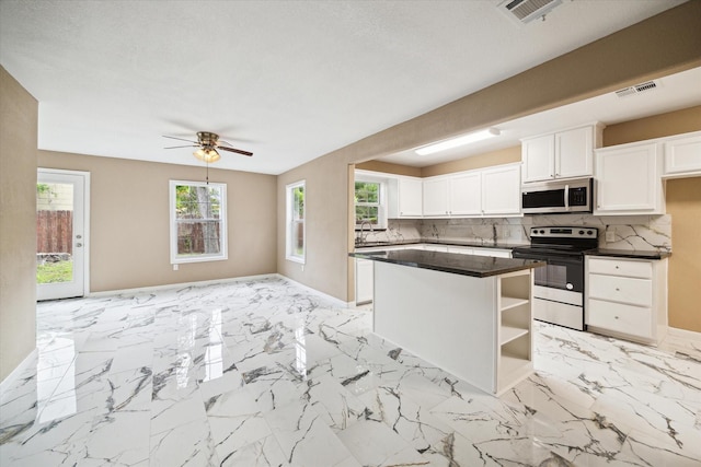 1904 Kansas St, Baytown, TX 77520 - kitchen featuring stainless steel appliances, dark countertops, baseboards, a center island, and white cabinetry