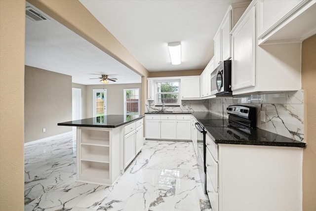 1904 Kansas St, Baytown, TX 77520 - kitchen featuring appliances with stainless steel finishes, a sink, a kitchen island, backsplash, and white cabinetry