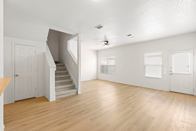 23831 Single Oak St, Spring, TX 77373 - unfurnished living room featuring a ceiling fan, light wood-style flooring, a textured ceiling, and stairs