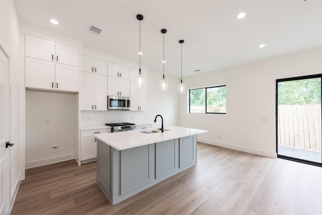 6135 Pacific Forest Dr, Houston, TX 77346 - kitchen featuring appliances with stainless steel finishes, light wood finished floors, white cabinetry, and recessed lighting