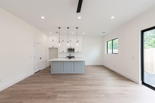 6135 Pacific Forest Dr, Houston, TX 77346 - kitchen with stainless steel microwave, white cabinetry, plenty of natural light, recessed lighting, and light wood-style flooring