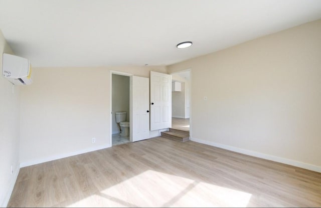 51 Blue Bonnet Ct, Lake Jackson, TX 77566 - unfurnished bedroom featuring a wall mounted AC, light wood-style floors, baseboards, and ensuite bathroom