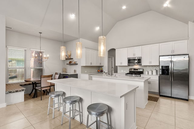 511 Summer Acres Ct, Rosenberg, TX 77469 - kitchen with appliances with stainless steel finishes, an island with sink, high vaulted ceiling, light tile patterned flooring, and a chandelier