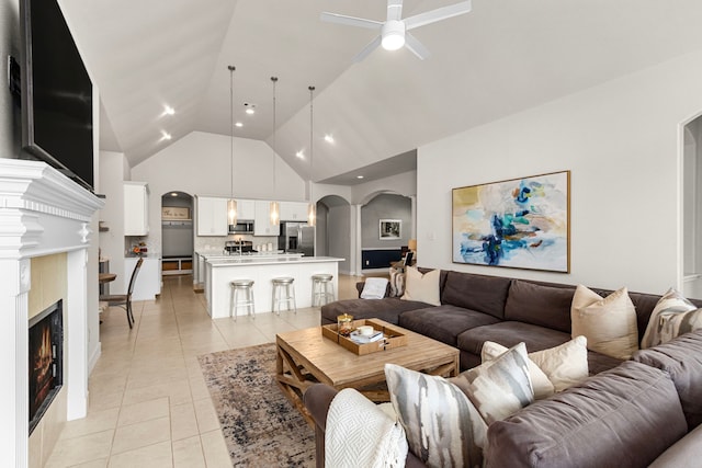 511 Summer Acres Ct, Rosenberg, TX 77469 - living area with arched walkways, a ceiling fan, light tile patterned floors, high vaulted ceiling, and a warm lit fireplace