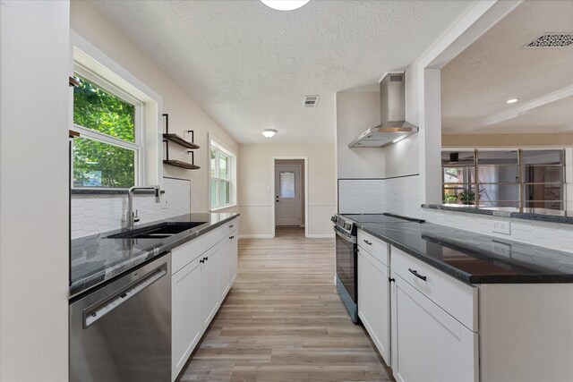 9863 Swan Ct, Conroe, TX 77385 - kitchen featuring wall chimney exhaust hood, appliances with stainless steel finishes, a sink, backsplash, and a textured ceiling