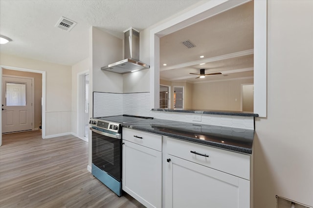 9863 Swan Ct, Conroe, TX 77385 - kitchen with wall chimney exhaust hood, stainless steel electric range oven, tasteful backsplash, white cabinets, and light wood-style floors