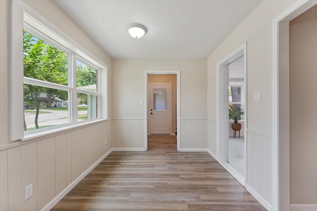 9863 Swan Ct, Conroe, TX 77385 - corridor with light wood-style floors, a wainscoted wall, and a textured ceiling