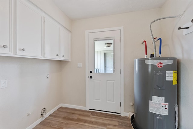 9863 Swan Ct, Conroe, TX 77385 - laundry area with electric water heater, gas dryer hookup, cabinet space, light wood finished floors, and baseboards